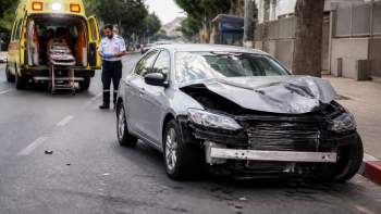 זירת תאונת דרכים ברחוב עירוני עם רכב פגוע ואמבולנס ברקע - עורך דין תאונת דרכים לנזקי גוף